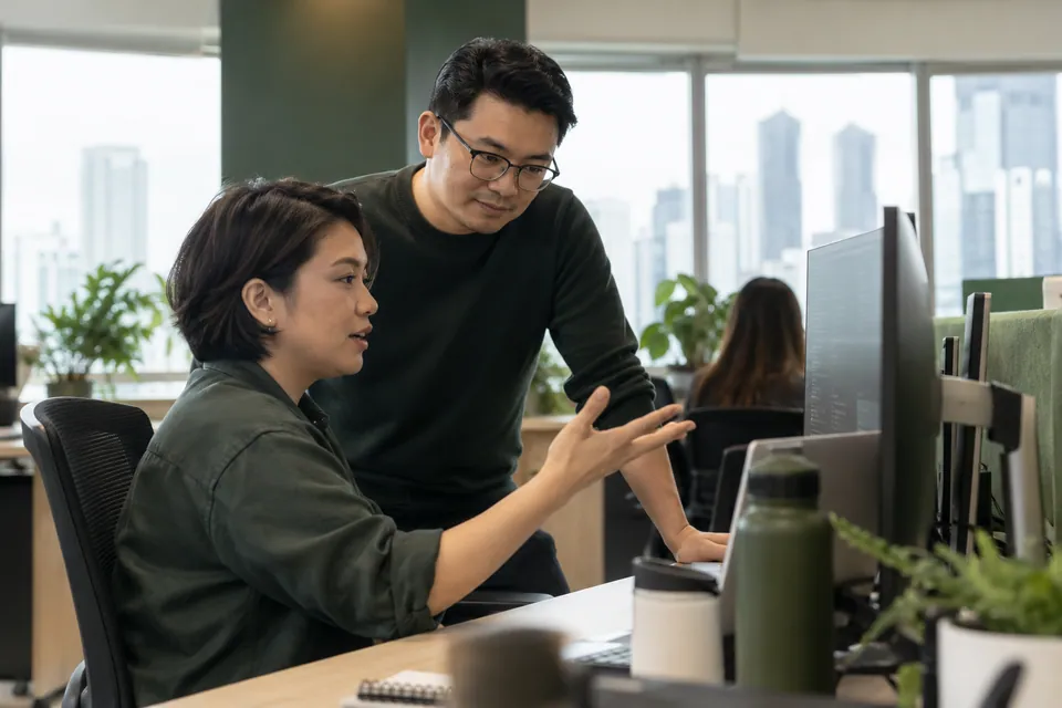 Software professionals discussing work at a workstation